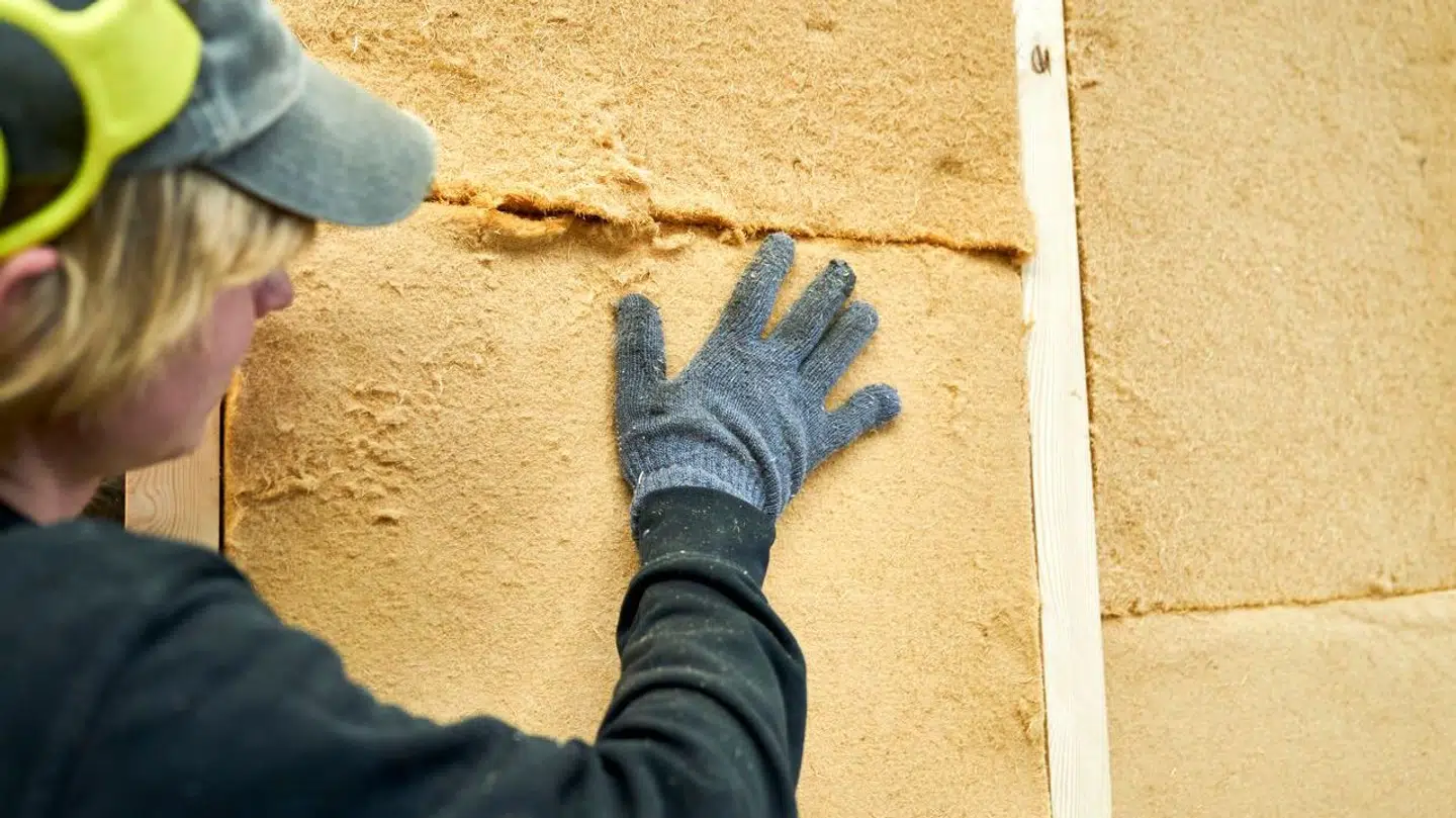 Mand med høreværn igang med at sætte isolering af træfiber op, København den 9. august 2021