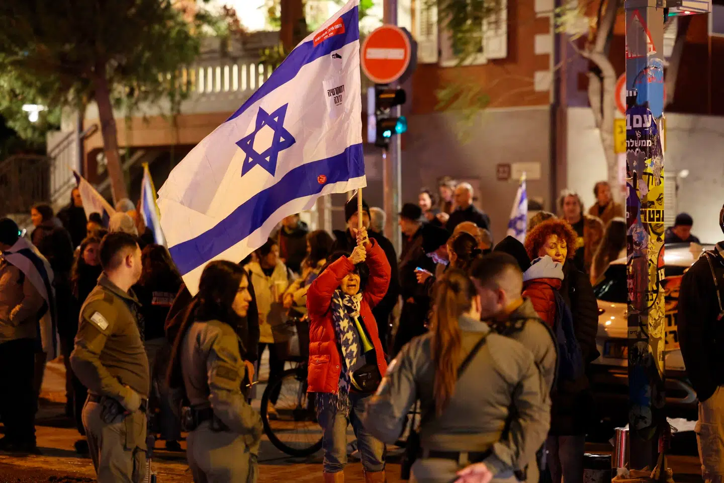 En kvinde holder det israelske flag ved en demonstration i Tel Aviv. Der demonstreres for, at den israelske regering går af, og at valget bliver rykket frem. Foto: Ahmad Gharabl, AFP / Scanpix