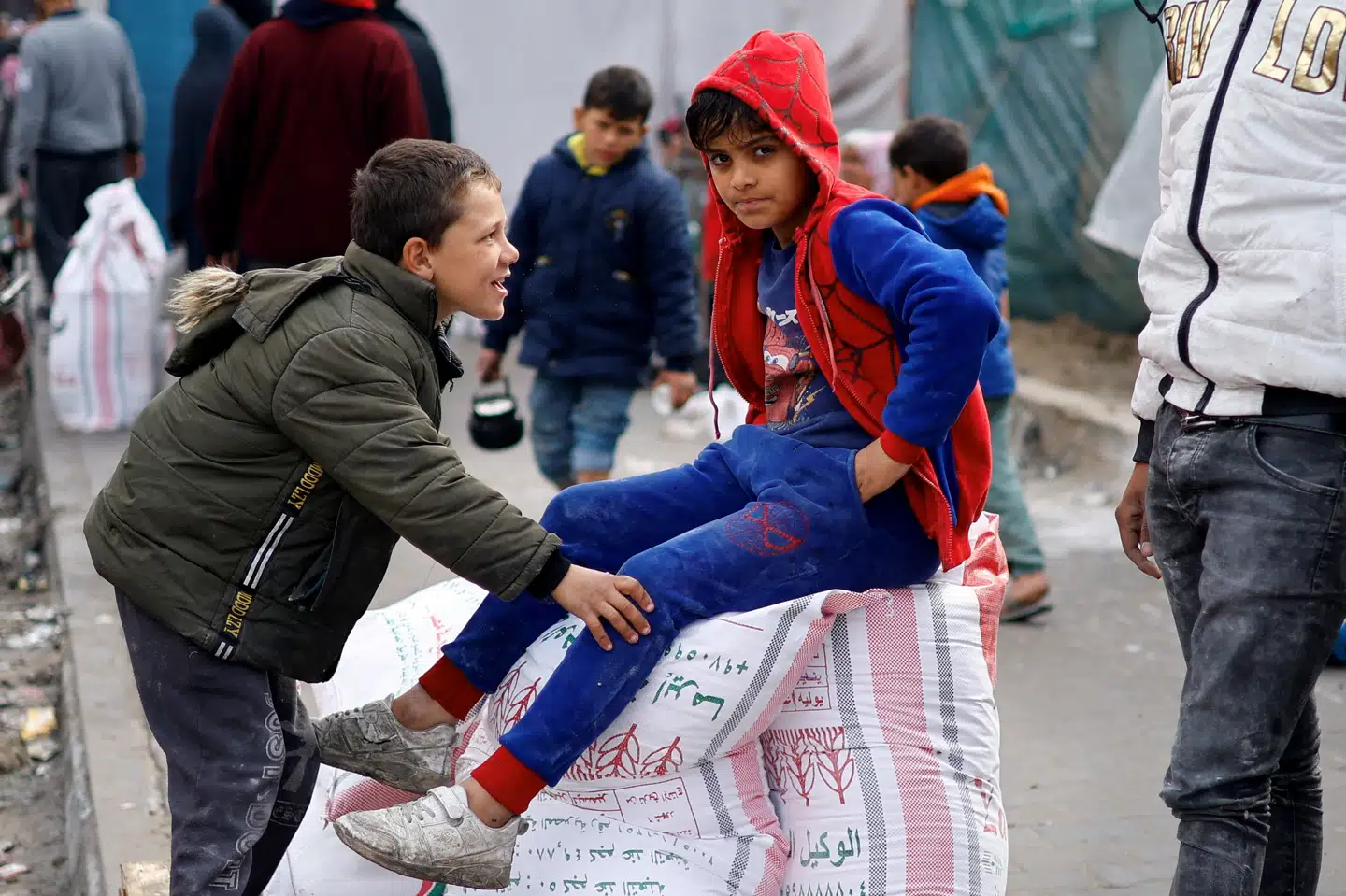 En palæstinensisk dreng sidder på melsække, som FN's hjælpeorganisation for palæstinensiske flygtninge (UNRWA) deler ud i byen Rafah, hvor omkring 1,5 millioner af Gazastribens indbyggere har søgt tilflugt for de israelske bombardementer.