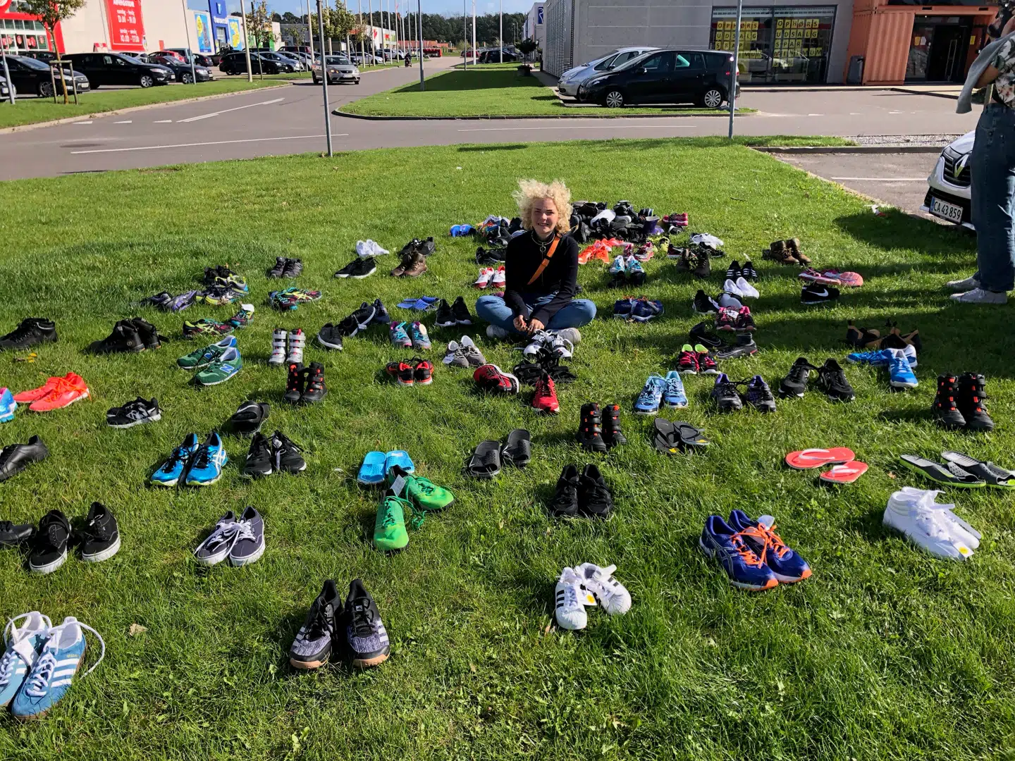 Sofe Kamp med alle skoene foran butikken i Holbæk. De vendte tilbage fredag eftermiddag for at vise deres utilfredshed med, at Sportmaster har smidt helt nye sko ud i en container, når de kunne være blevet doneret til genbrug.