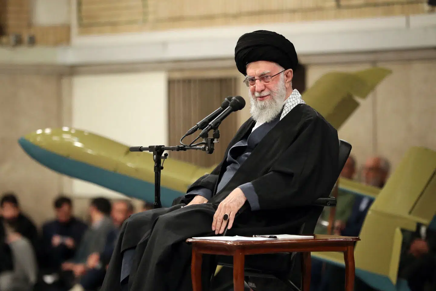 Irans øverste leder, Ayatollah Ali Khamenei, som her sidder i et militærmøde med en kaman-12-drone bag sig, er blevet bandlyst fra Facebook og Instagram, har selskabet Meta oplyst.