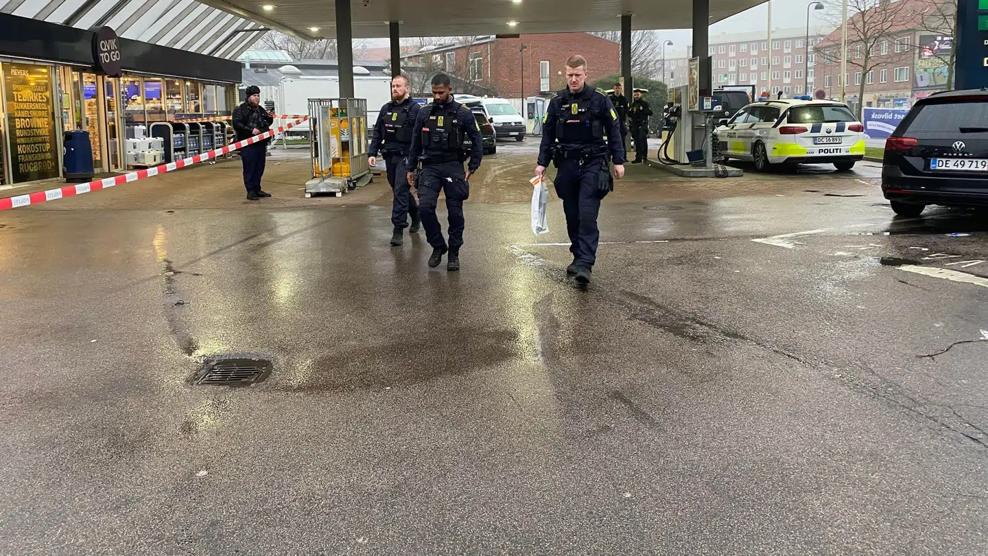 Betjente bærer bevisposer væk fra gerningsstedet.