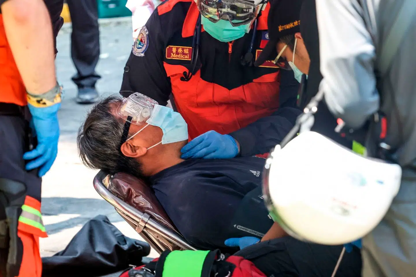 En såret mand køre væk på en båre efter at være blevet fanget i en ødelagt bygning i New Taipei City under jordskælvet.