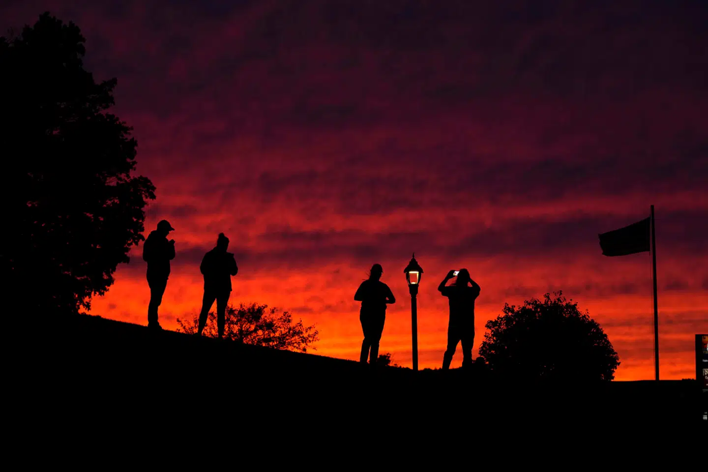 Visitors photograph the evening sky in advance of Hurricane Lee, Friday, Sept. 15, 2023, in Bar Harbor, Maine. Red skies at night usually portend fair weather but Saturday's weather is predicted to be stormy. (AP Photo/Robert F. Bukaty)