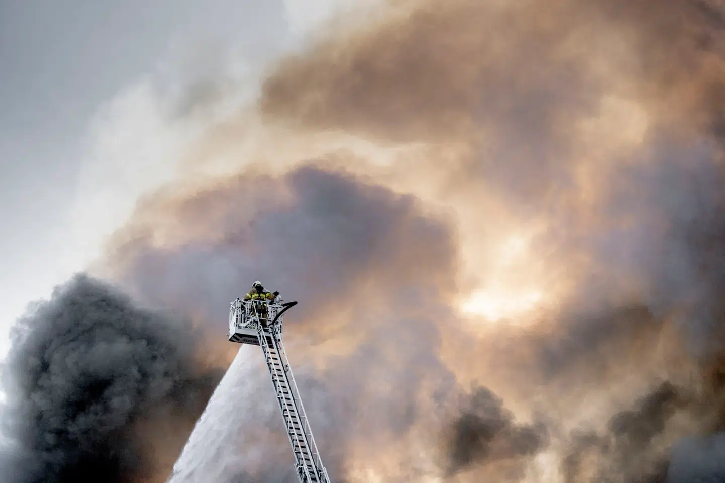 En ene brandmand kæmper mod flammerne højt over jorden.