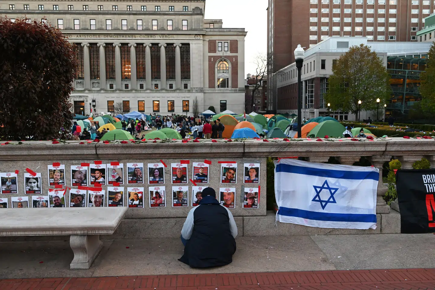 I nærheden af Columbia-lejren har jødiske studerende oprettet et »space«, der dog næppe kan betegnes som »safe«. Her ses en mand bede foran portrætterne af nogle af de forsvundne gidsler, der blev bortført til Gaza. Foto: Andrea Renault, Scanpix