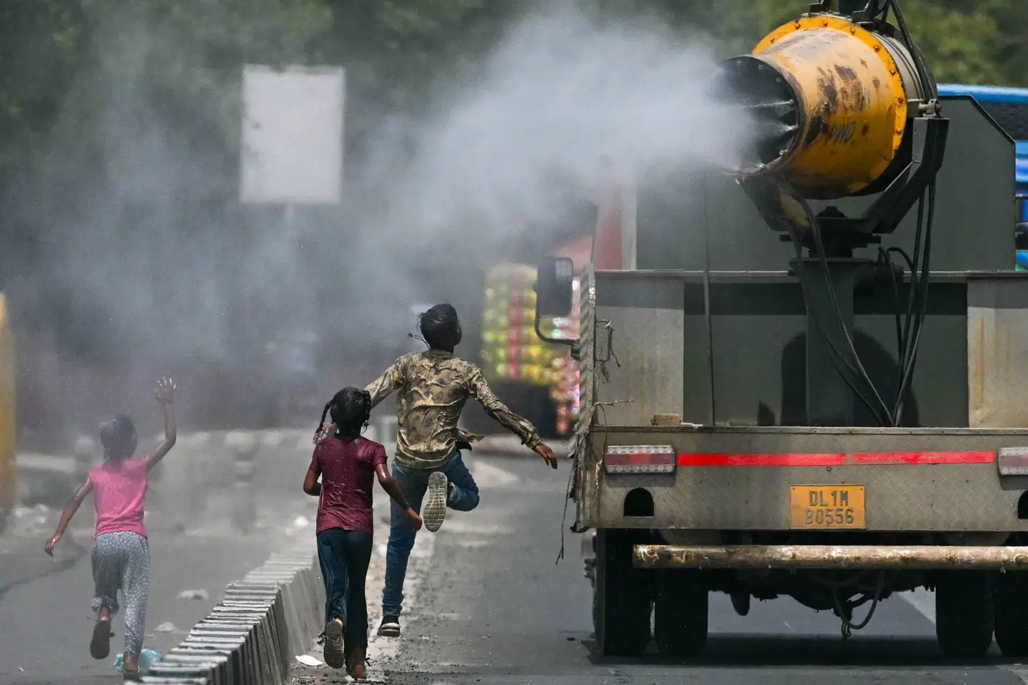 Børn i New Delhi løber efter en lastbil, der sprøjter vand på gaden. 52,3 grader stod der på termometeret onsdag eftermiddag i en forstad til den indiske hovedstad.