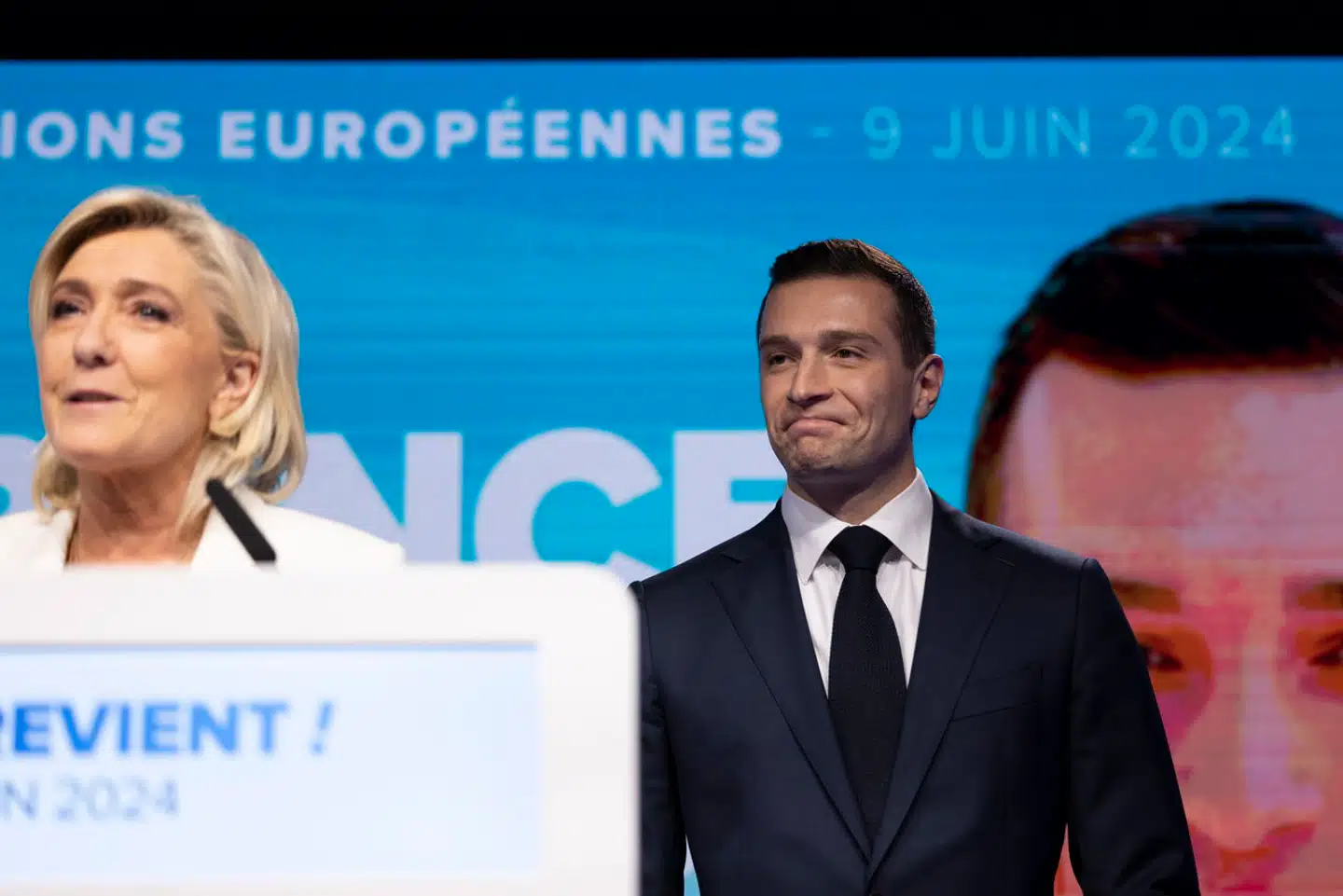 Rassemblement Nationals spidskandidat, Jordan Bardella, smiler en anelse stift, mens Marine Le Pen kommenterer præsident Emmanuel Macrons beslutning om at udskrive valg.