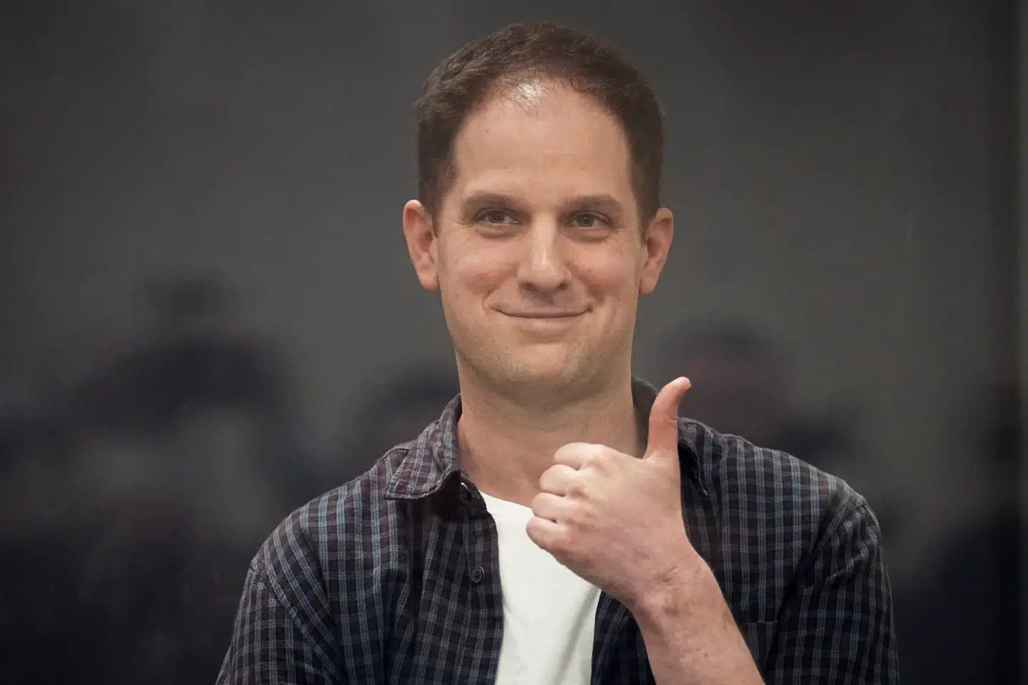 Den amerikanske journalist Evan Gershkovich giver tegn inde fra et glasbur i et retslokale i Moskva i april.