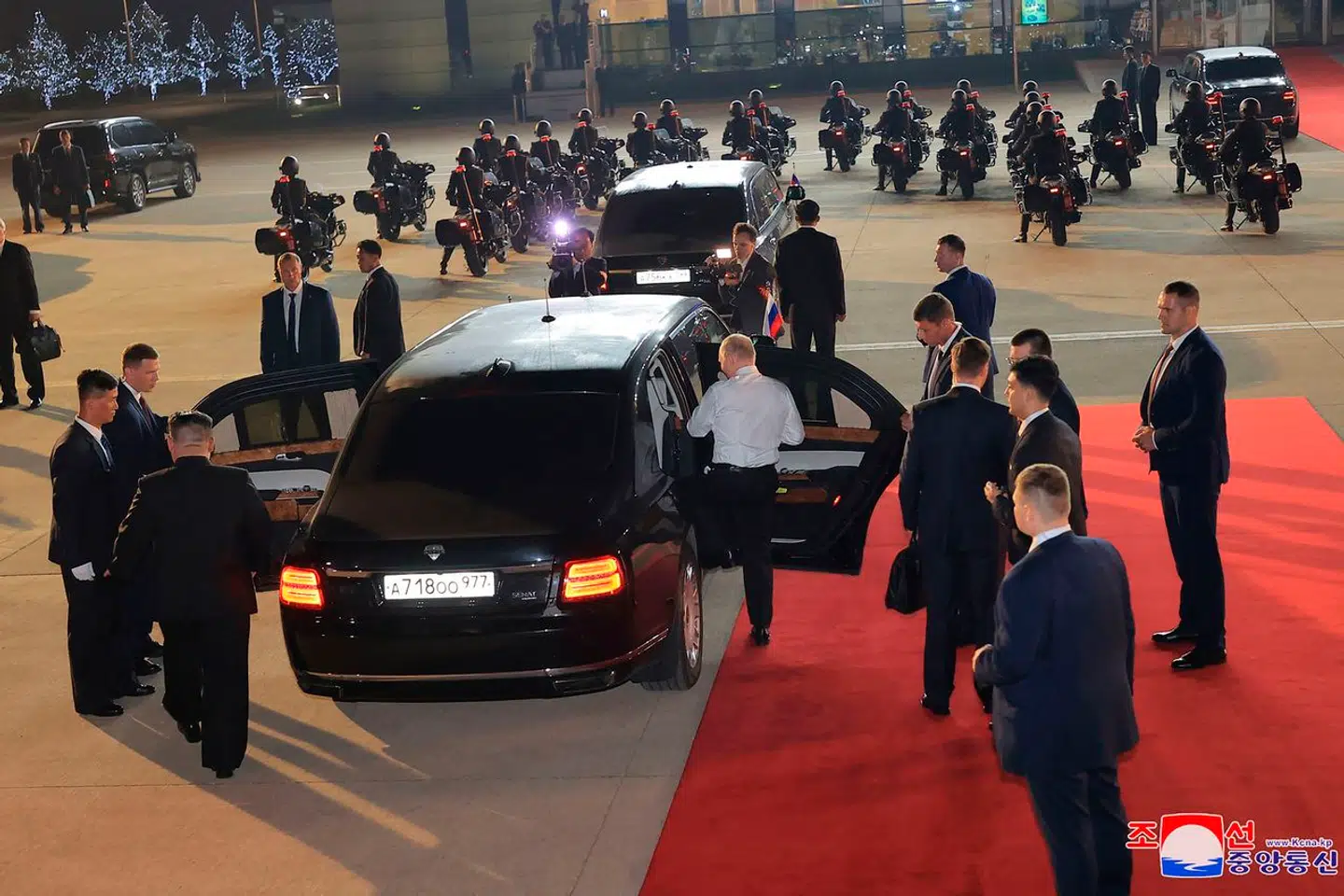 Vladimir Putin smider hurtigt jakken, mens Kim Jong-un går rundt om bilen.