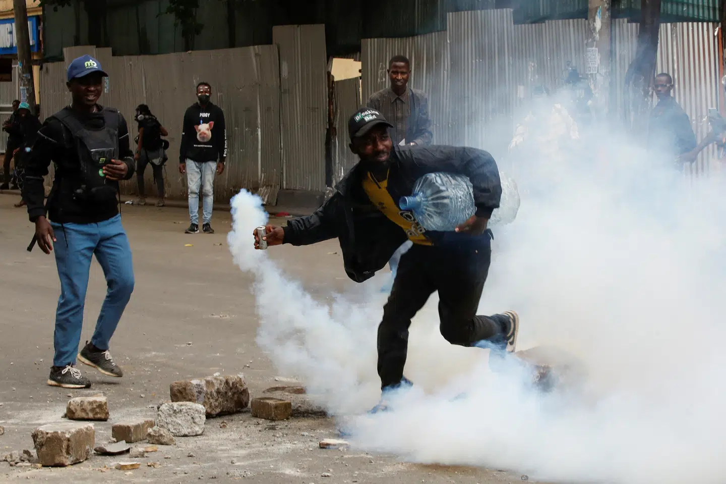 En demonstrant samler en tåregasgranat op under voldsomme gadekampe i Nairobi torsdag. Demonstranterne har overvejende været under ledelse af unge fra generation Z, som åbenlyst har fået myndighederne til at veksle mellem en hård linje og kompromissøgende udspil.