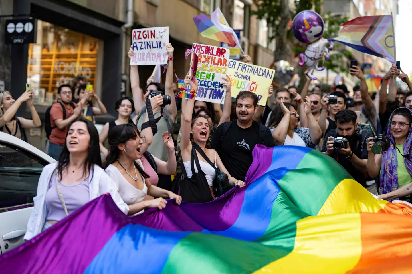 LGBT+-personer og deres støtter holder et stort regnbueflag og råber slagord ved søndagens arrangement i Istanbul, som er forbudt af myndighederne.