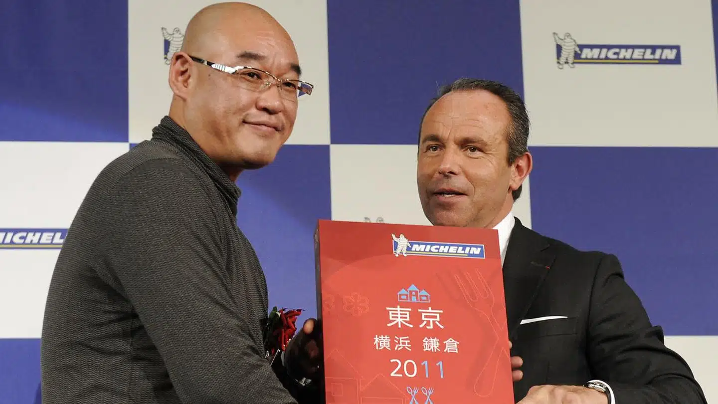 Michelin Guides direktør Jean-Luc Naret (th.) overrækker Mitsuhiro Araki (tv.) en forstørret udgave af 2011s Michelin Guide, hvor Araki første gang fik tilddelt tre michelinstjerner. Nu har de ingen.