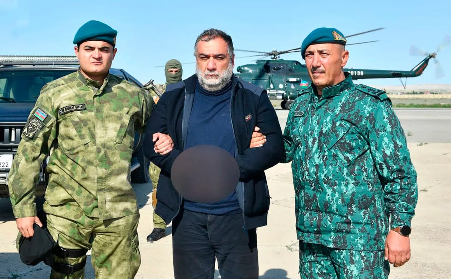 I midten ses Ruben Vardanjan, der holdes af to aserbajdsjanske sikkerhedsfolk. Han skulle angiveligt sidde fængslet i Aserbajdsjan tiltalt for at have finansieret terror og ulovligt at have krydset en grænse.