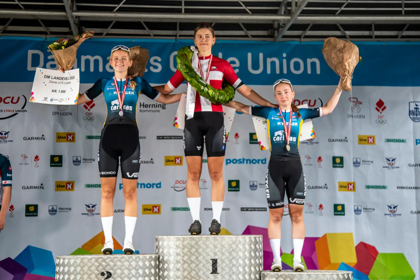 Her ses Alma Walther Møller Rasmussen på toppen af podiet efter mesterskabet i landevejscykling for U19-kvinder, hvor hun var hurtigere end Mathilde Cramer (tv) og Ida Krickau (th).