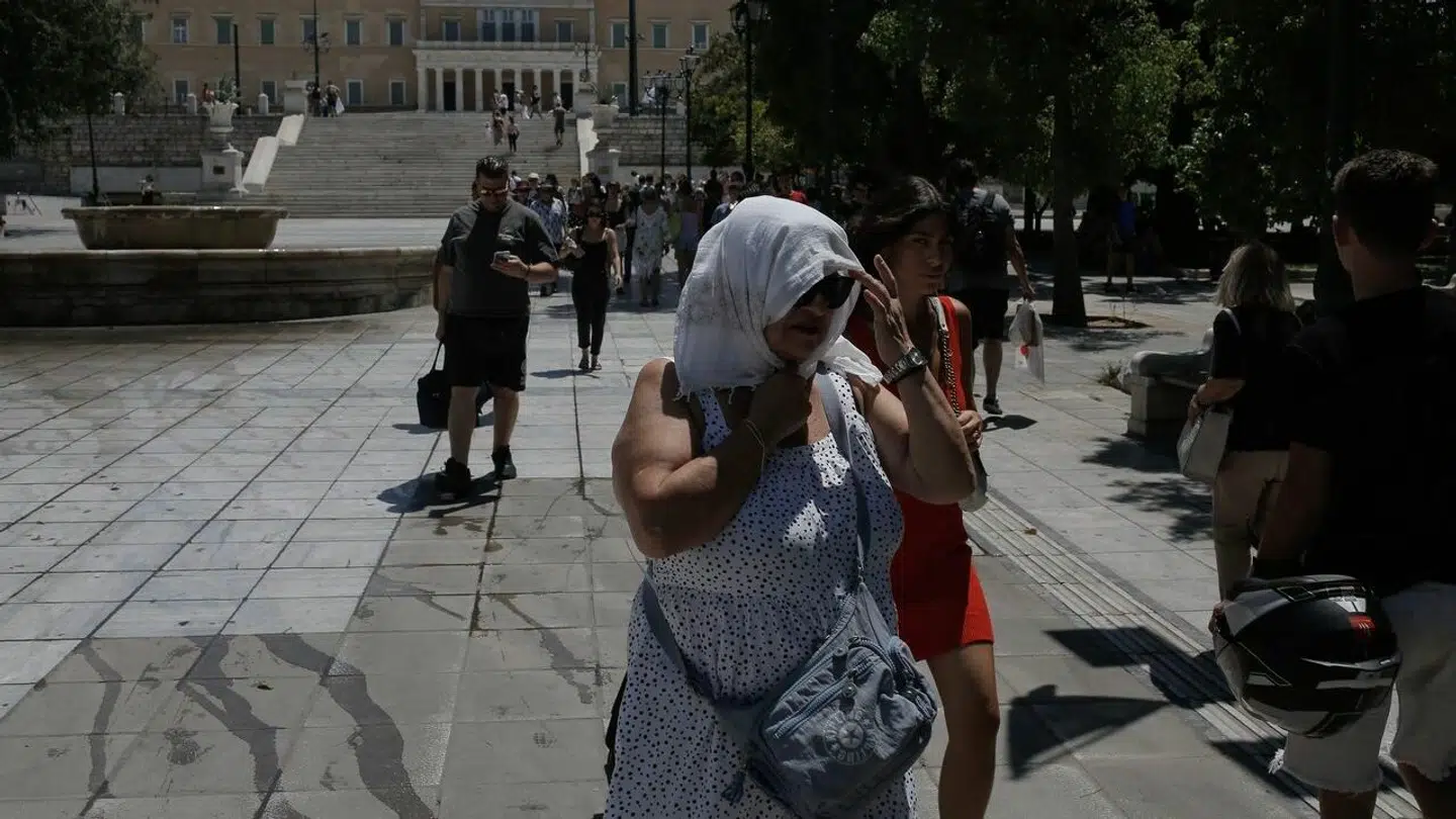 En kvinde skærmer sig mod solen i Athen.