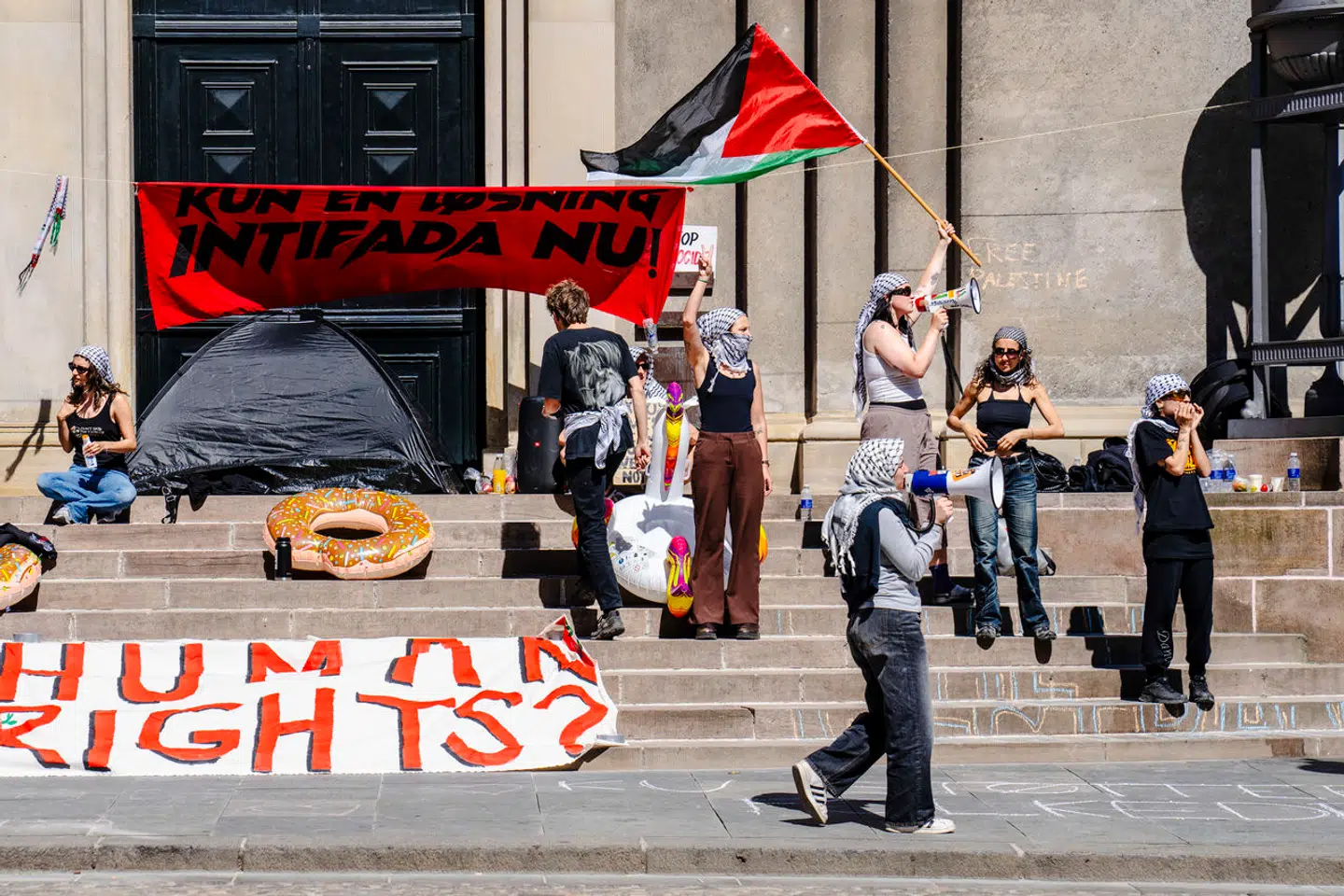 »Vi mener, KU har bevist, at det kan udgøre et positivt eksempel på en institution, der forholder sig mere ansvarligt til den ulovlige besættelse,« skriver kronikørerne. På billedet blokerer demonstranter indgangen på Frue Plads til Københavns Universitet fredag 17. maj 2024. (Foto: Thomas Traasdahl/Scanpix 2024)