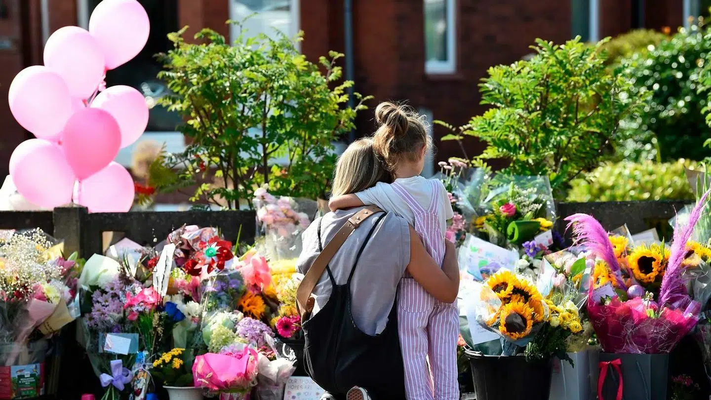 Området omkring gerningsstedet er præget af blomster, balloner og beskeder. Andre steder i byen – og nu flere dele af Storbritannien – er derimod præget af vrede og had.