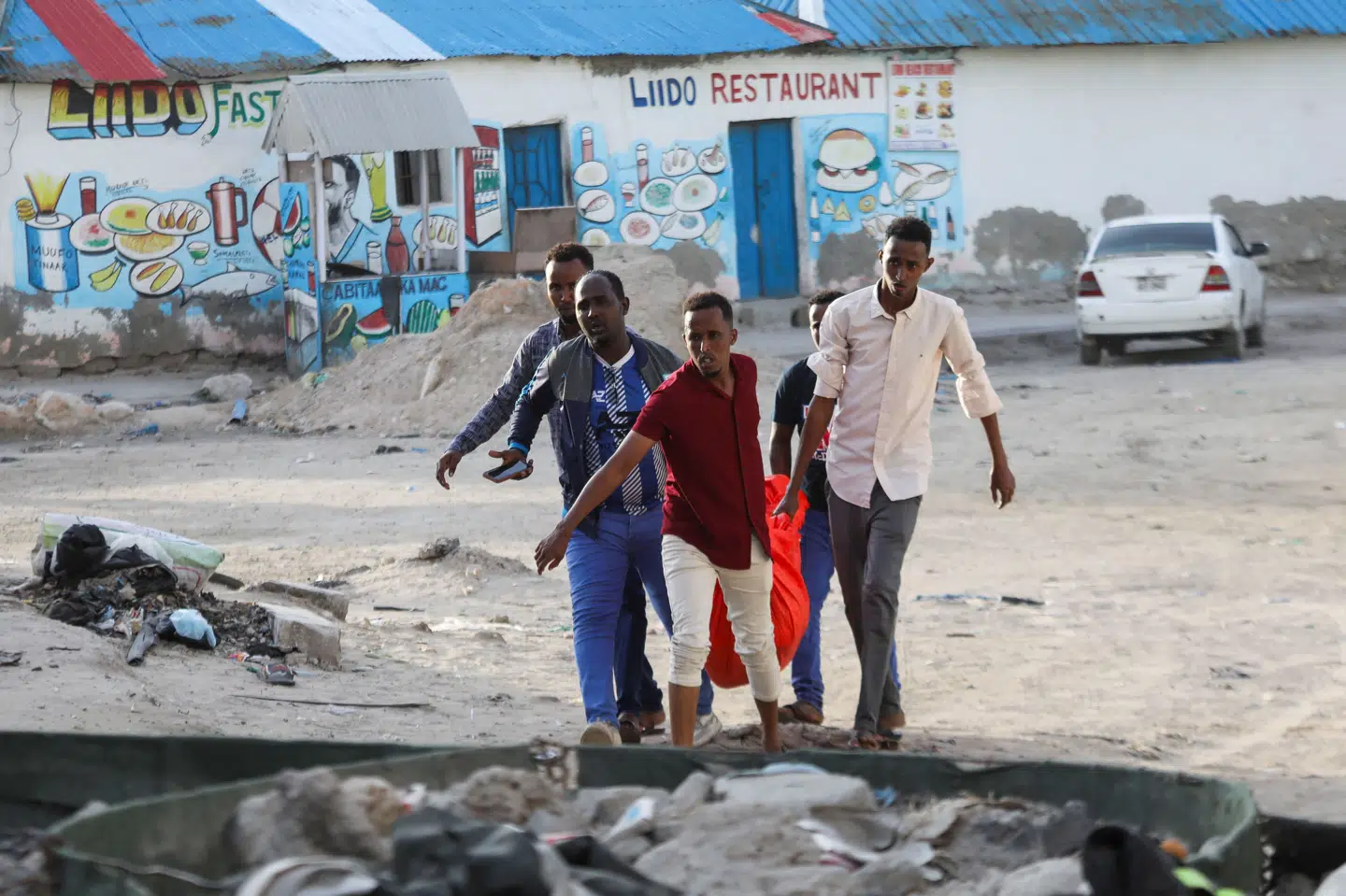 Folk bærer liget af en kvinde væk efter et blodigt angreb sendt fredag på civile på en populær strand i Somalias hovedstad, Mogadishu.
