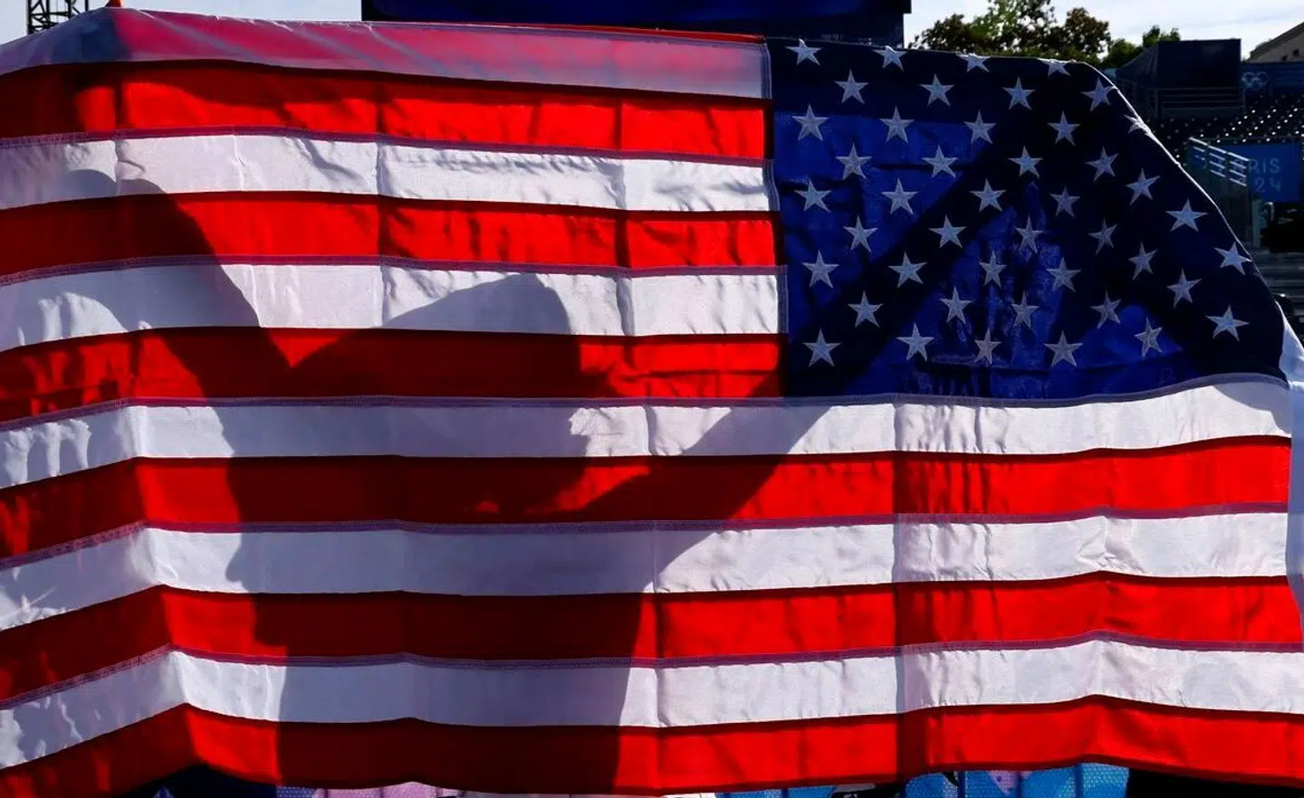 US' Kristen Faulkner celebrates with a US flag after winning the women's cycling road race during the Paris 2024 Olympic Games in Paris, on August 4, 2024. (Photo by David GRAY / AFP)
