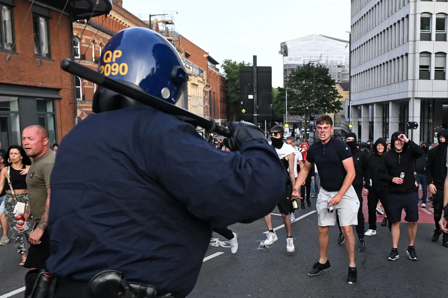 Kampklædte betjente konfronterer 3. august højreradikale demonstranter i Bristol. En X-konto, der kalder sig "Europe Invasion" var med til at udløse uroligheder i England ved at sprede falske historier om, at en muslim knivdræbte tre små piger i byen Southport". Nu står samme konto bag falske oplysninger om drabet på en 14-årig pige i Landskrona i Sverige. - Myrdet af muslimske indvandrere, hedder det på X, det tidligere Twitter.