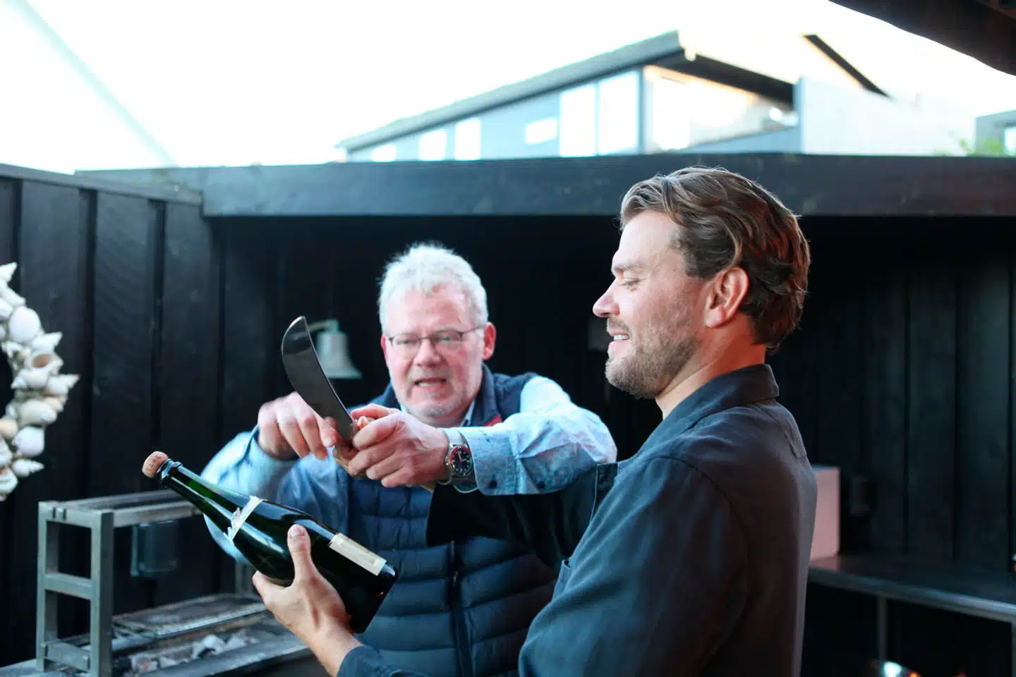 Marni lærer Pilou Asbæk at sable en flaske champagne.