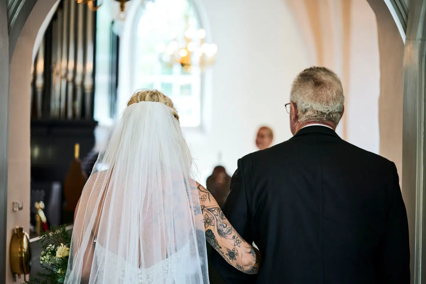 »Traditionen grunder i de gamle mønstres patriarkalske dominans og reducering af kvinden til en genstand, der skifter ejer, og kan tolkes meget negativt, hvis man vil,« skriver Sørine Gotfredsen. På billedet føres bruden ind i Søllerød Kirke 31. juli 2021.