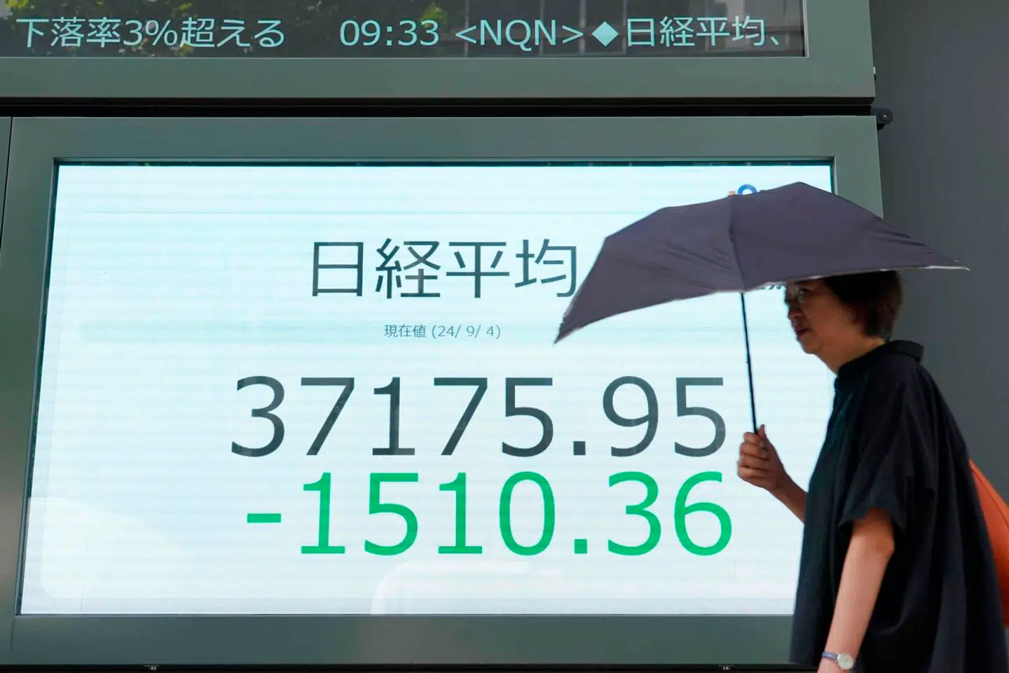 Det japanske børsindeks Nikkei faldt onsdag morgen, dansk tid, med mere end 3,50 procent. Her går en kvinde forbi Tokyo-børsens informationstavle.