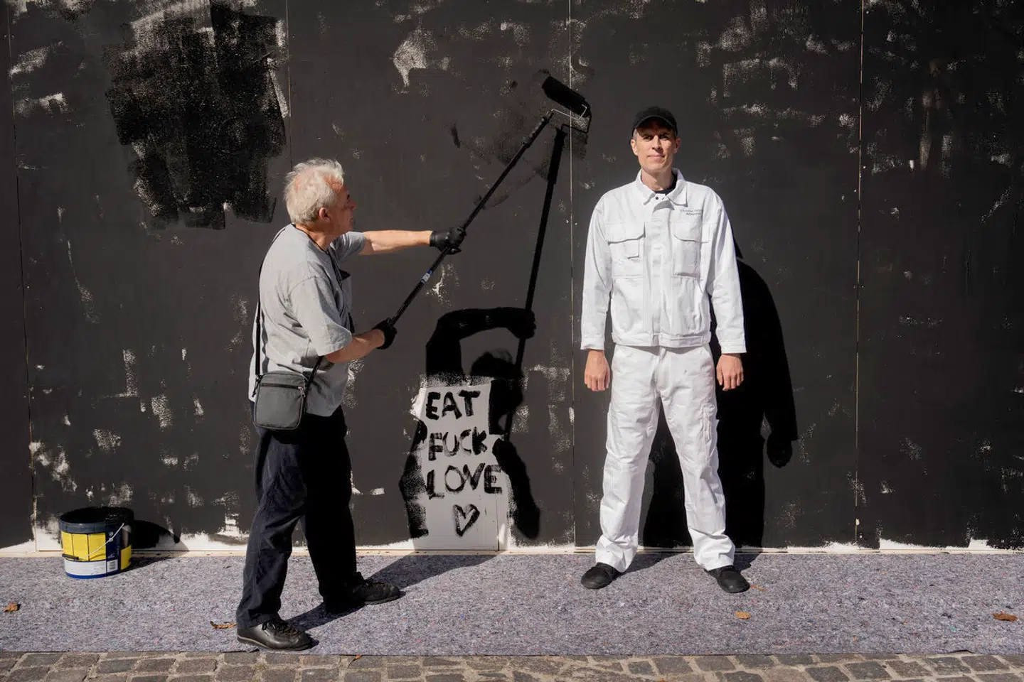 Christian Falsnaes i hvidt tøj ved værket ARBEJDSTID. Fotografen Stuart McIntyre kom tilfældigt forbi og er godt i gang med at levere en ordentlig arbejdsindsats.