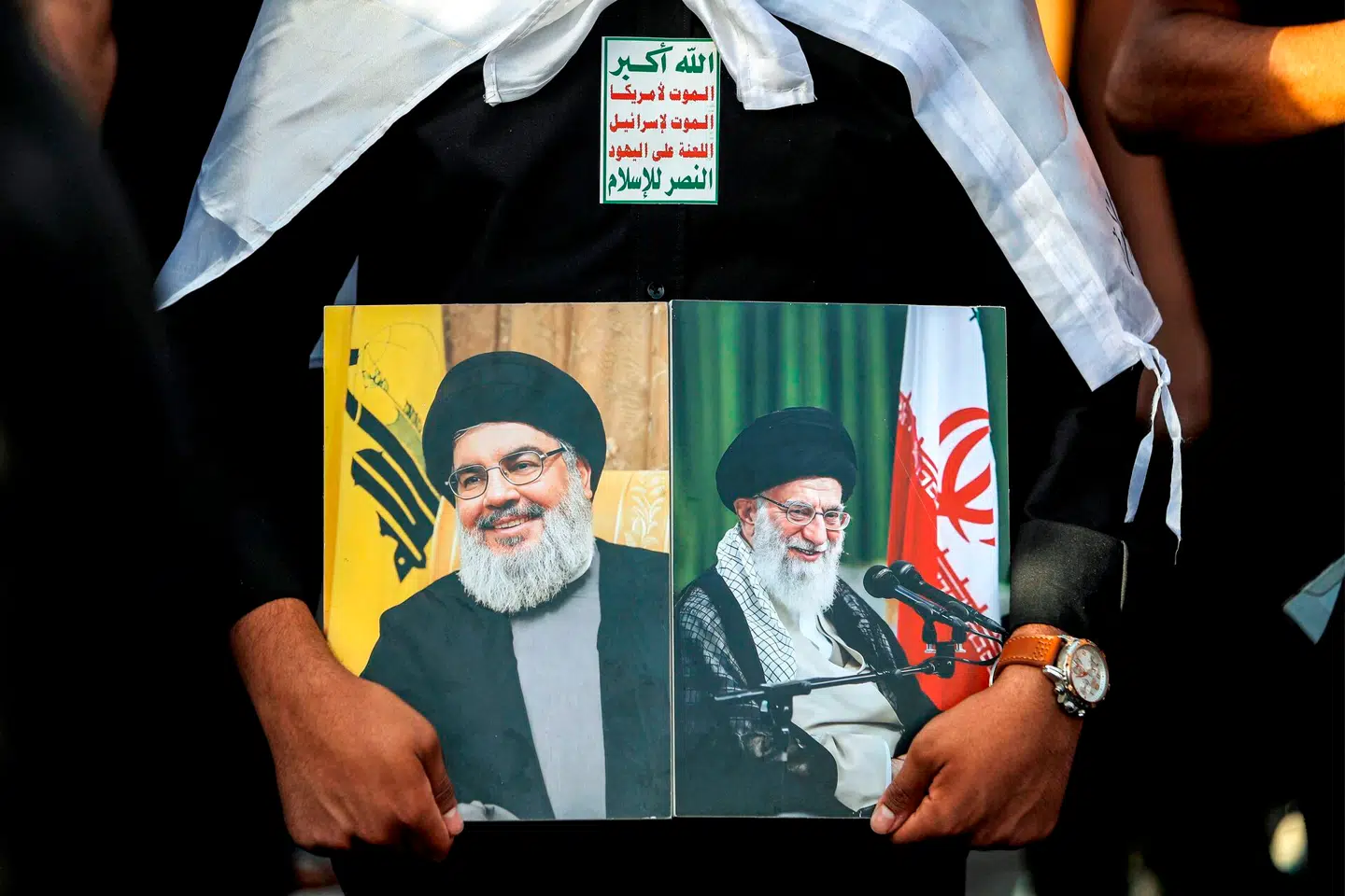 En mand fremviser en collage med Hizbollahs nu afdøde Hassan Nasrallah og Irans Ayatollah Ali Khamenei. Foto: Ahmah Al-Rubaye, AFP / Scanpix