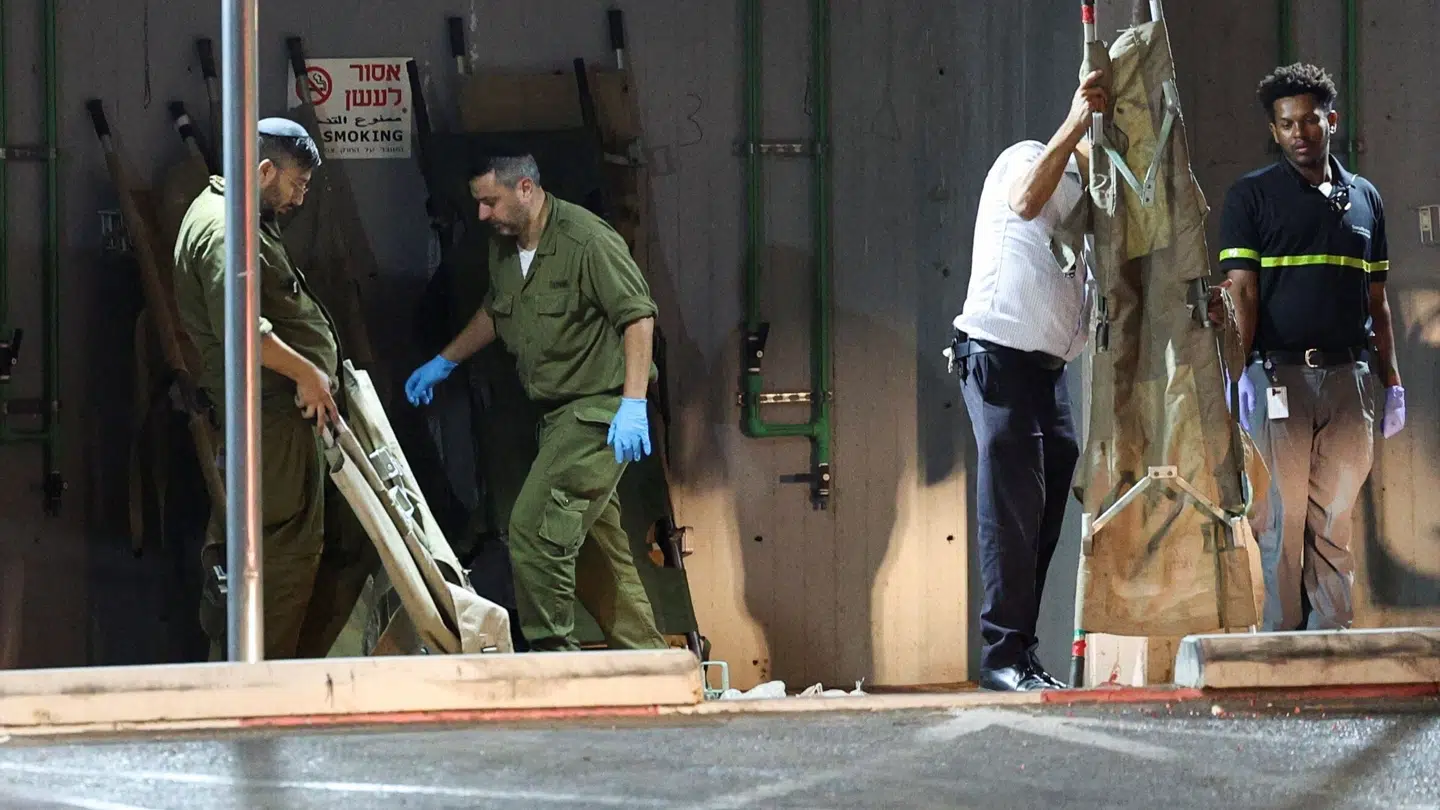 Israelske soldater og ambulancefolk henter bårer til sårede fra droneangrebet på det nordlige Israel søndag aften.