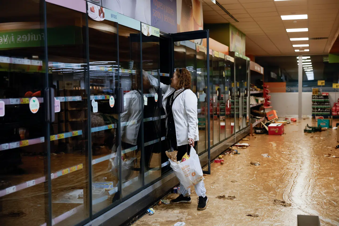 En kvinde er i gang med at tage mad fra køleskabet i et supermarked i Paiporta i Valencia-regionen.