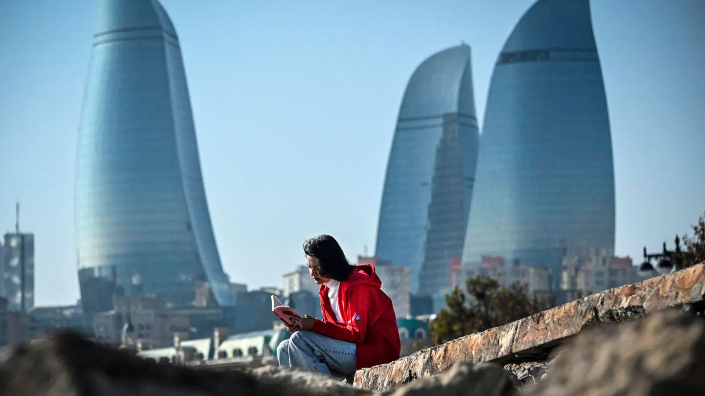 En kvinde sidder foran Flame Towers, et af landemærkerne i det centrale Baku i Aserbajdsjan, den 10. november 2024, på tærsklen til FN's klimakonference. FN's klimakonference i 2024.