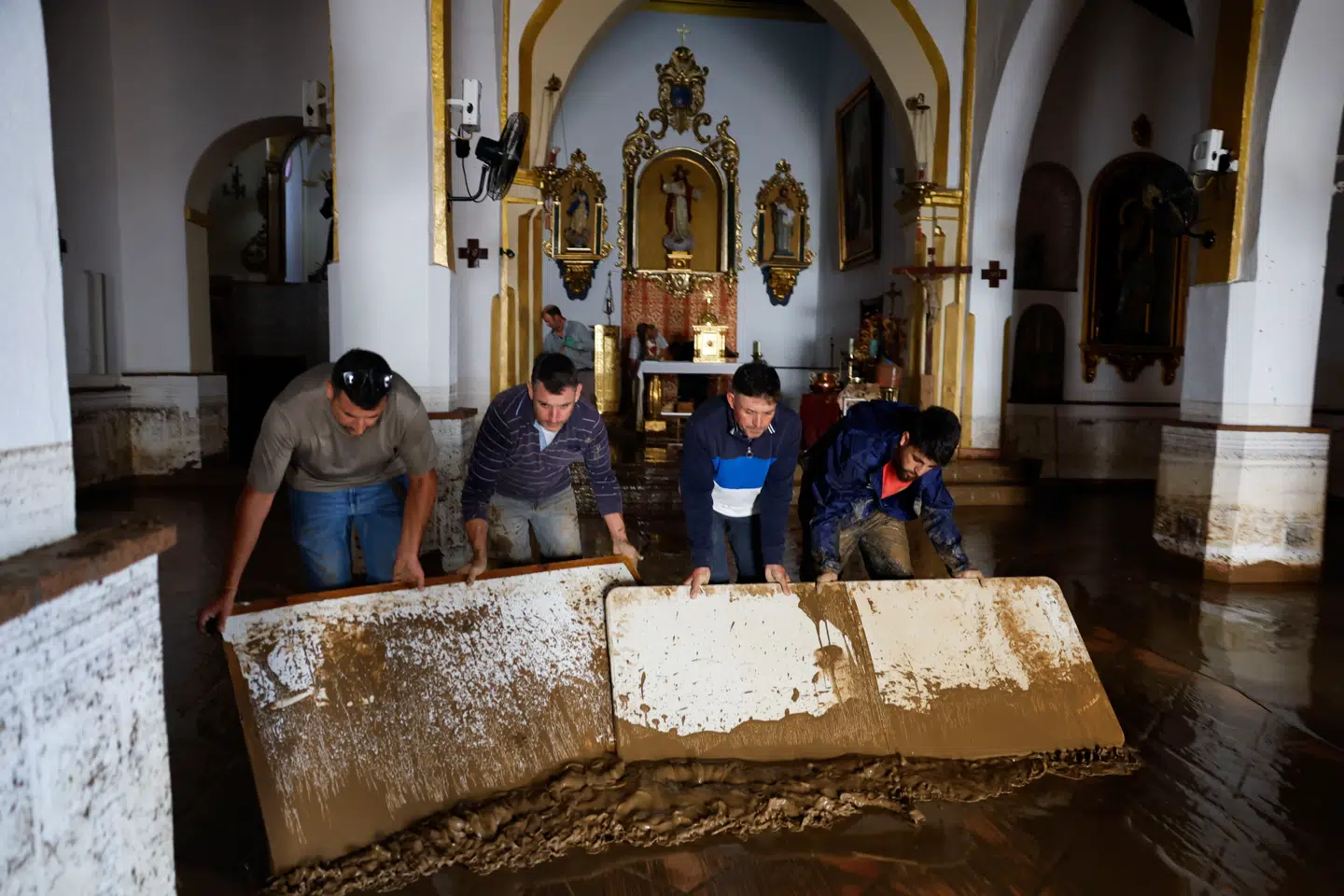Lokale fjerner mudder og vand fra en kirke i Malaga efter de voldsomme regnmængder onsdag.