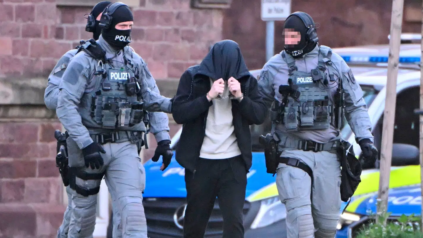 Politiet eskorterer en af de anholdte bort.