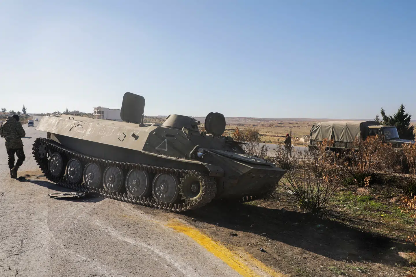 Et medlem af den alliance af oprørere, der har vundet frem i det nordlige Syrien i denne uge, går ved et militærkøretøj i Maarat al-Numan i Idlib-provinsen søndag. Russisk luftvåben er kommet præsident Assads regeringsstyrker til undsætning, meddeler Rusland.