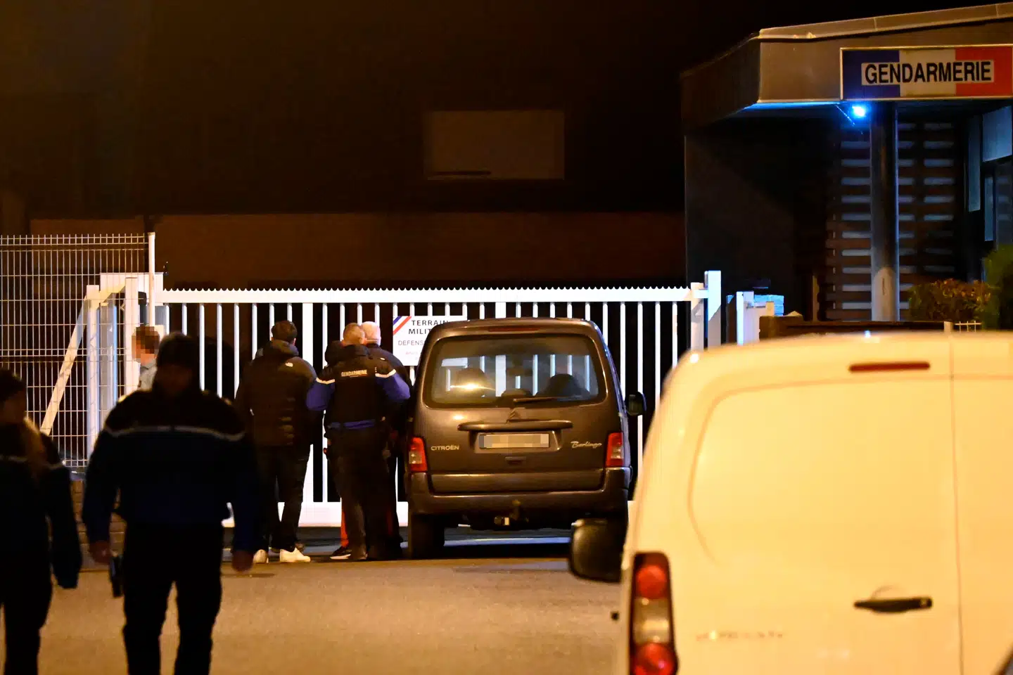 Pårørende til den formodede gerningsmand ankommer til en gendarmeristation, mens franske gendarmer står ved siden af et køretøj til højre, som angiveligt tilhører den mistænkte.