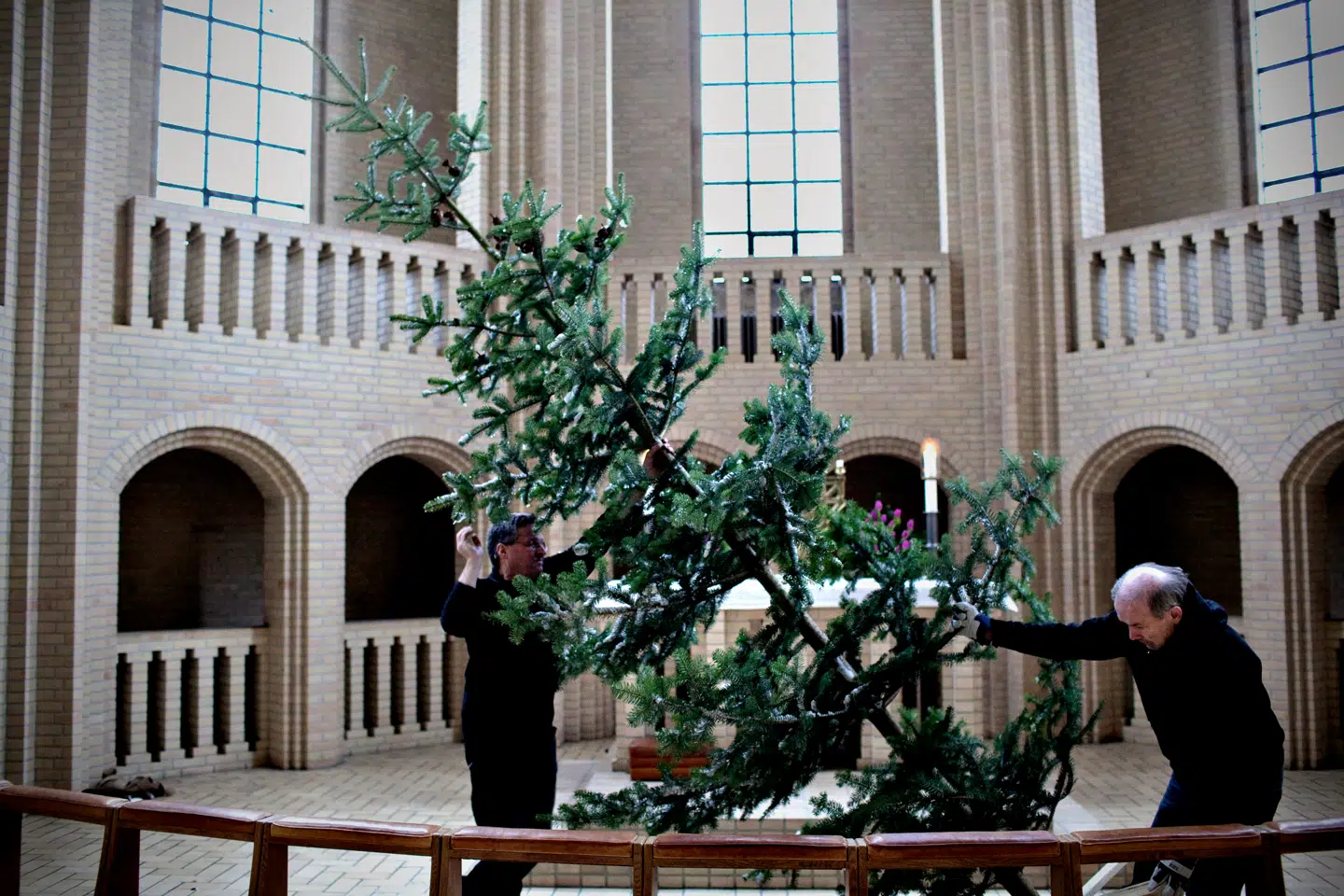 »Vi kan alle sammen falde igennem og have brug for hjælp, på den ene eller den anden måde. Julen minder os om den fælles udsathed, men også det, som vi fælles kan gøre for hinanden,« skriver kronikørerne. Kirketjenere rejser et juletræ og pynter i Grundtvigs Kirke.