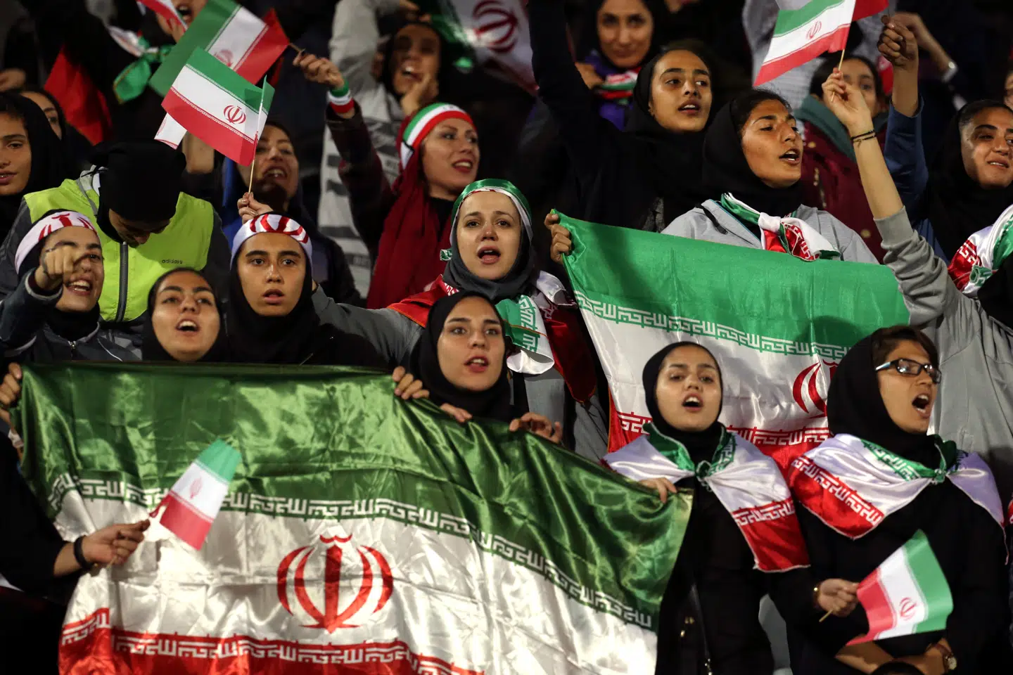 Kvindelige iranske fodboldtilskuere vifter med iranske flag under en kamp mellem Iran og Bolivia på Azadi Stadion i Teheran i 2018, hvor iranske myndigheder i en sjælden gestus tillod en udvalgt gruppe af kvinder at overvære en herrelandskamp.