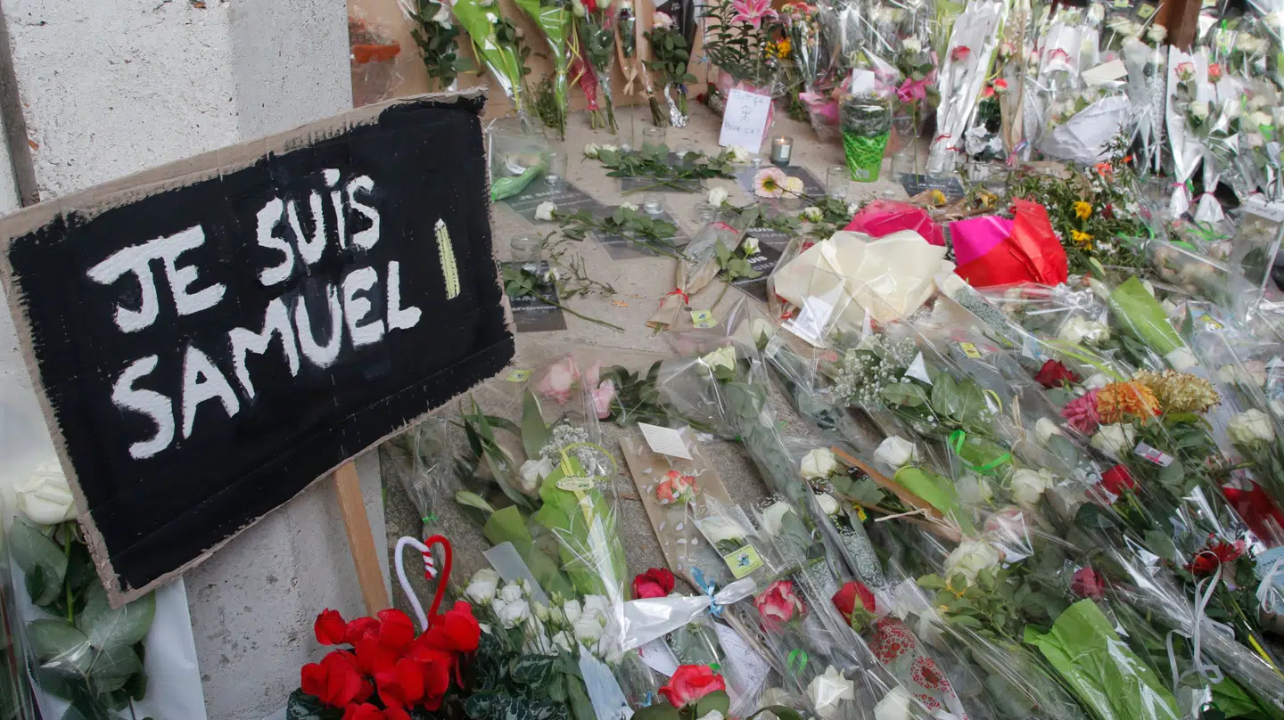 Samuel Paty blev slået ihjel i 202. Her ses en plakat med teksten »Jeg er Samuel« på fransk og blomster ligger uden for den skole, hvor den dræbte historielærer arbejdede, lørdag den 17. oktober 2020 i Conflans-Sainte-Honorine, nordvest for Paris.