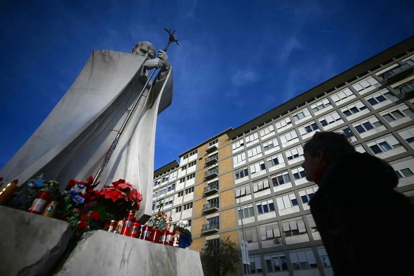 En person står ved en statue af den tidligere pave Johannes Paul II udenfor Gemelli-hospitalet i Rom, hvor den 88-årige pave Frans bliver behandlet for bronkitis.