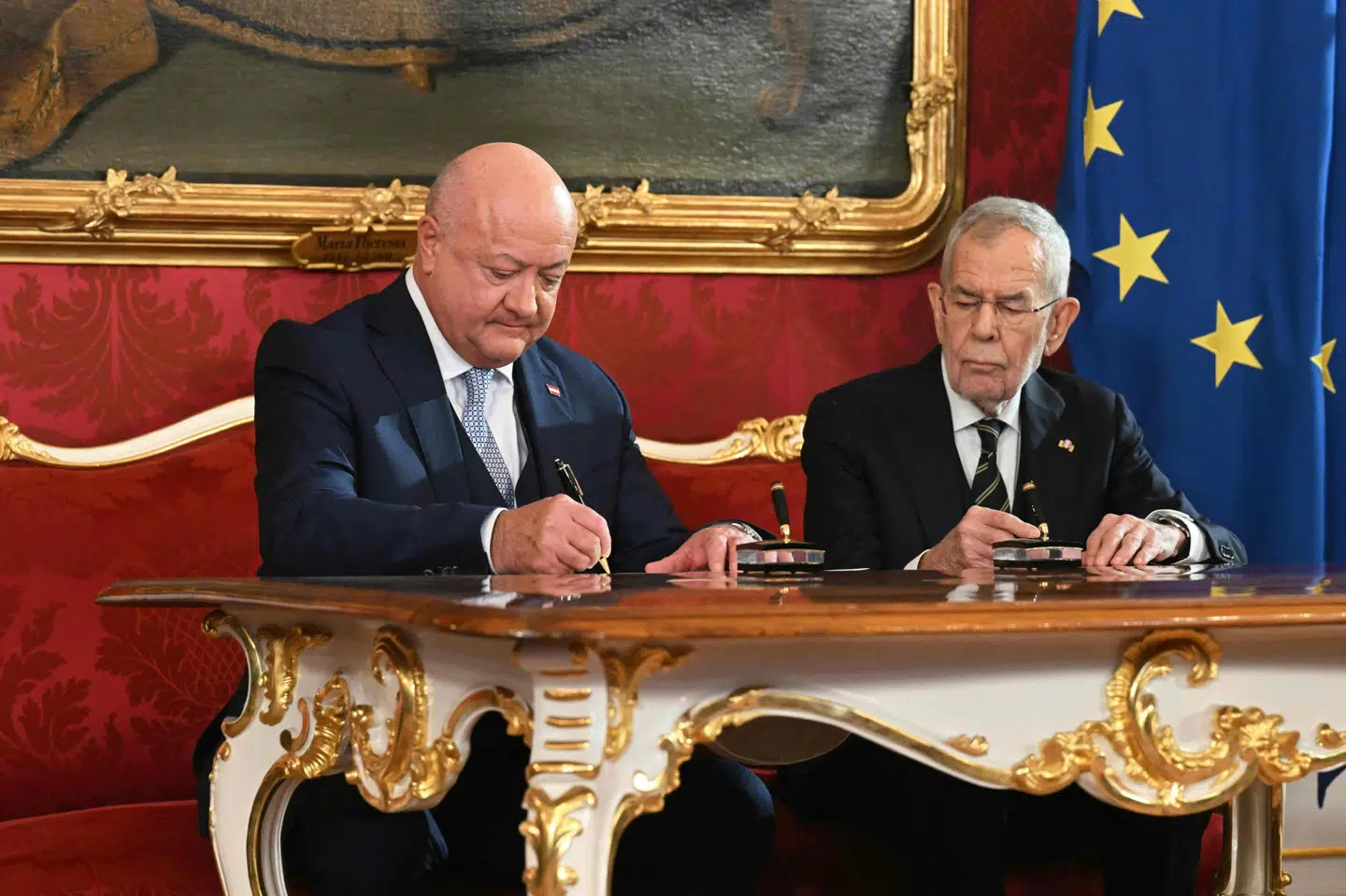 Østrigs nye forbundskansler, Christian Stocker (t.v.) fra det konservative parti ÖVP, underskriver dokumenter sammen med Østrigs præsident, Alexander Van der Bellen (t.h.), under indsættelsesceremonien i Wien mandag.
