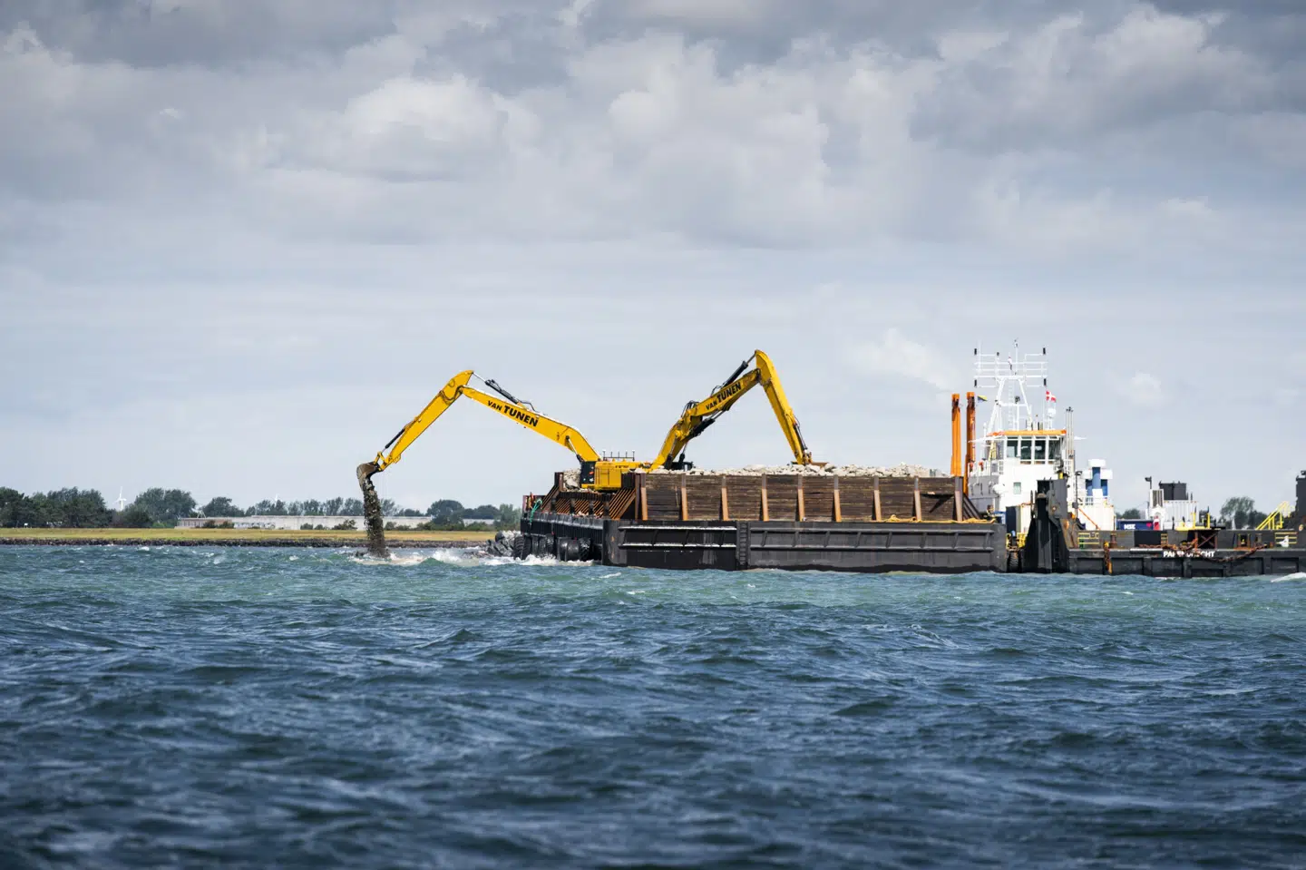 Allerede for fem år siden var der fuld gang i byggeriet af Femernforbindelse. Her ser man, hvordan der lægges tonsvis af sten i vandet til en mole i forbindelse med byggeriet af forbindelsen. (Arkivfoto)