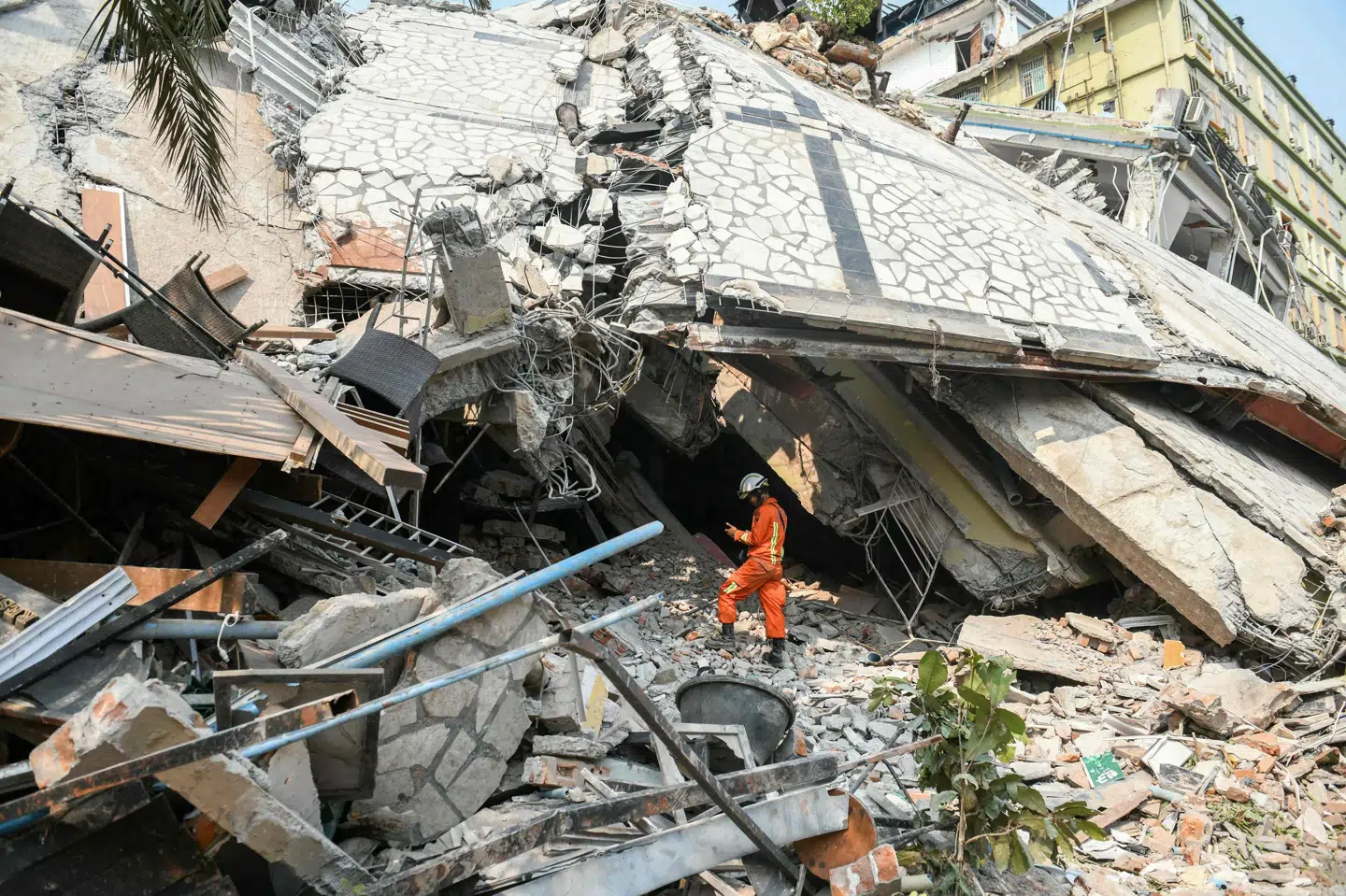 En redningsarbejder står foran boligblokken Sky Villa Condominium, hvor mere end 90 mennesker frygtes at være fanget under ruinerne.