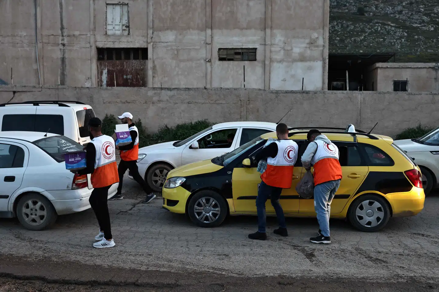 Frivillige fra Palæstinensisk Røde Halvmåne uddeler vand og mad til bilister, der venter på at komme igennem en israelsk kontrolpost ved byen Beit Furik i nærheden af den nordligt beliggende by Nablus på Vestbredden 26. marts. Organisationen melder søndag, at otte af deres nødhjælpsarbejdere er fundet døde efter angreb på ambulancer i Gaza i sidste uge.