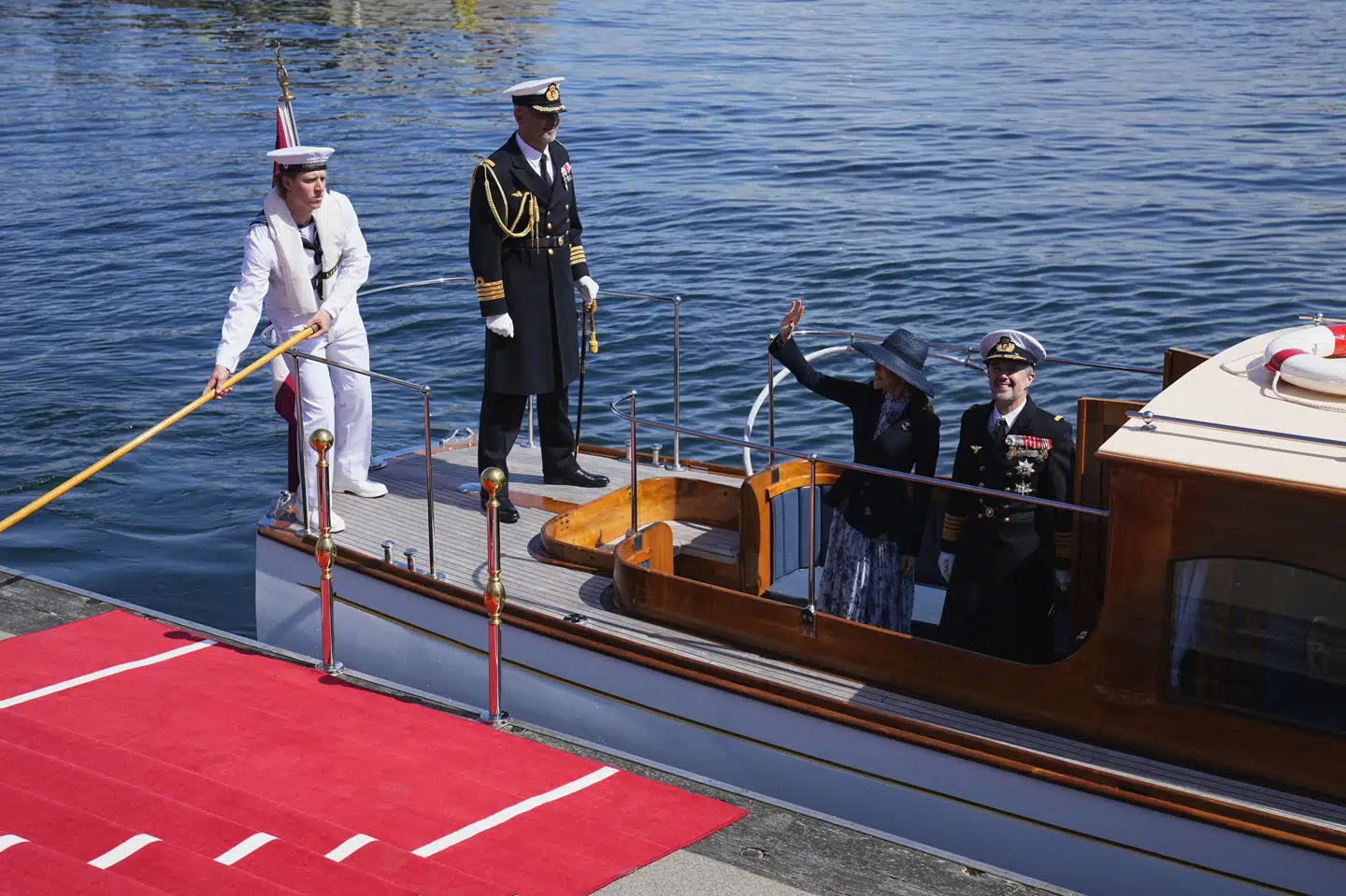 Dronning Mary vinkede til de fremmødte ved Nordre Toldbod, da hun og kong Frederik steg om bord på en lille chalup, der sejlede dem ud til kongeskibet "Dannebrog".
