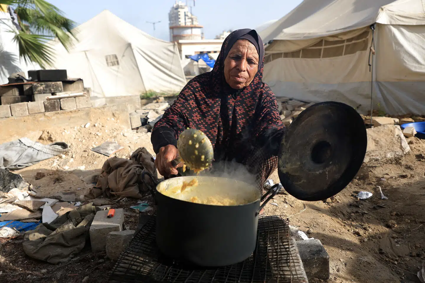 En palæstinensisk kvinde, som er blandt de mange fordrevne i Gazastriben, laver mad i en teltlejr i Gaza By søndag. I over to måneder er der ikke kommet nødhjælp ind til indbyggerne i Gazastriben, men nu siger Israel god for en ny amerikansk plan.