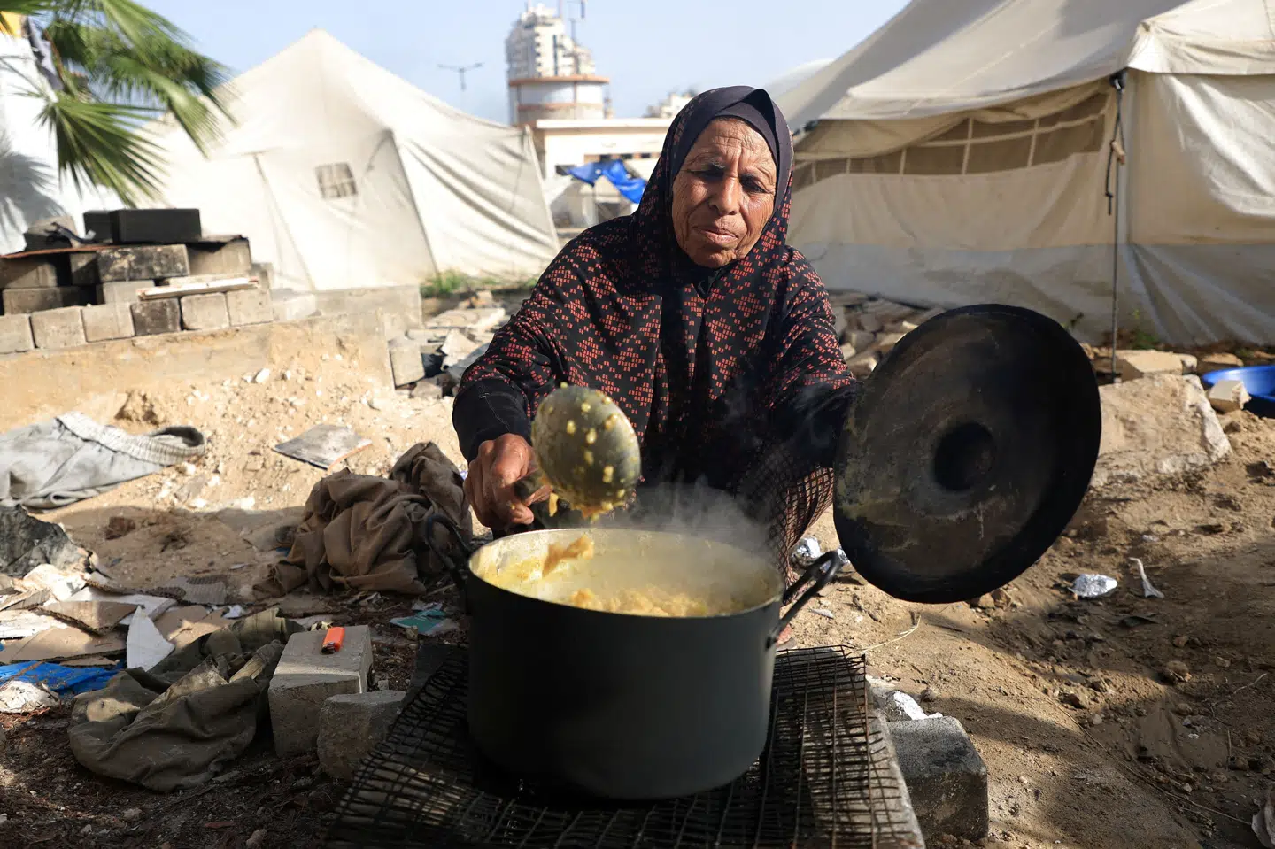 En palæstinensisk kvinde, som er blandt de mange fordrevne i Gazastriben, laver mad i en teltlejr i Gaza By søndag. I over to måneder er der ikke kommet nødhjælp ind til indbyggerne i Gazastriben, men nu siger Israel god for en ny amerikansk plan.