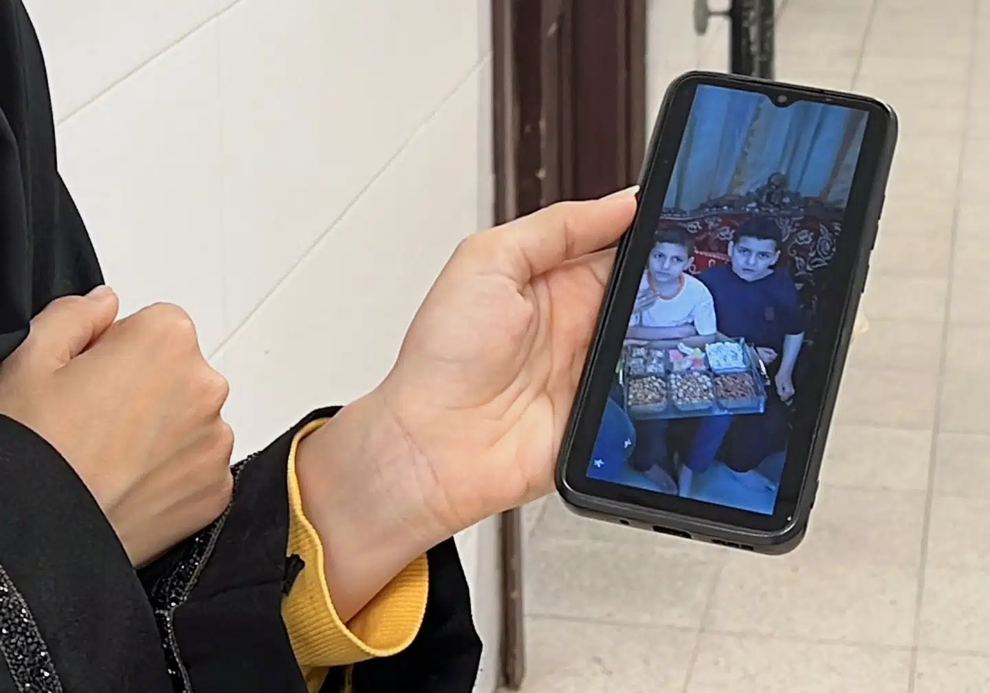 En kvinde på hospitalet, hvor børnelæge Alaa al-Najjar arbejder, viser et billede af to af børnelægens børn, der blev dræbt i et israelsk luftangreb i Khan Younis.