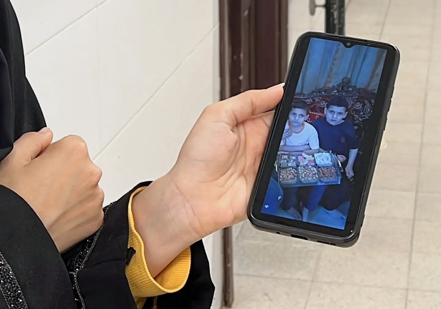 En kvinde på hospitalet, hvor børnelæge Alaa al-Najjar arbejder, viser et billede af to af børnelægens børn, der blev dræbt i et israelsk luftangreb i Khan Younis.